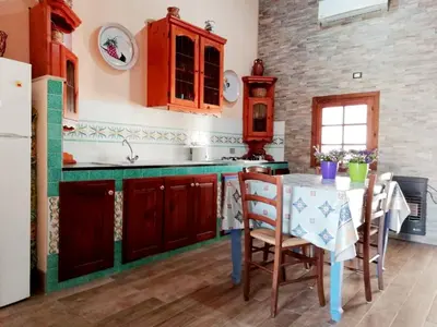a kitchen with wooden cabinets and a table with chairs at Casa Marina con vista sul castello in Castellammare del Golfo