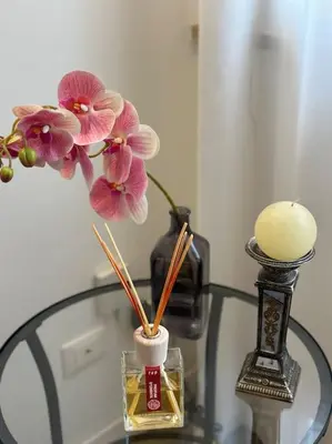 a glass table with flowers in a vase and a candle at coppola home in Palermo
