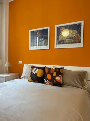 a bedroom with an orange wall and a bed with pillows at coppola home in Palermo