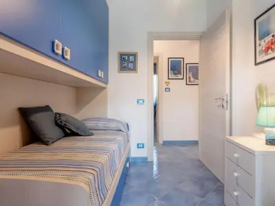 a small bedroom with a bed and a blue wall at Villa Olivella by Interhome in Cefalù
