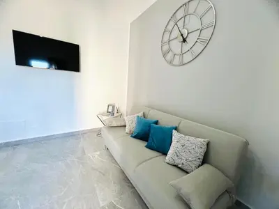 a living room with a couch and a clock on the wall at Soevi Appartamenti in Carini