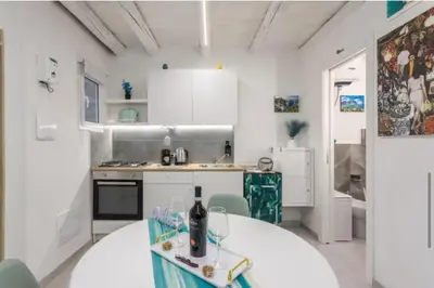 a white kitchen with a table with a bottle of wine at Apartment al Vicolo 27 in Palermo