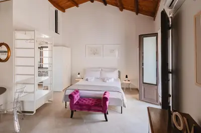 a bedroom with a large bed and a pink chair at Masalia Loft in Palermo