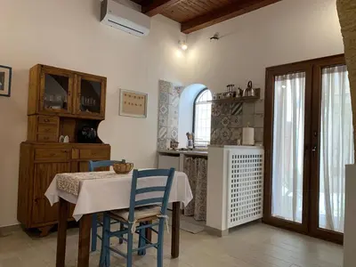 a dining room with a table and chairs and a kitchen at Guzzari 75 Home in Castellammare del Golfo
