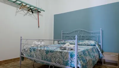 a bedroom with a bed with a blue wall at Umàri Rooms in Castellammare del Golfo