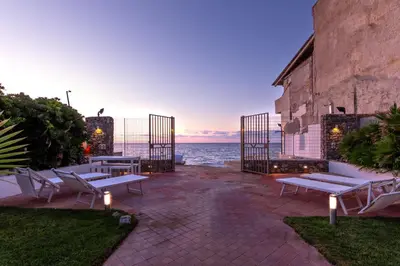 a patio with benches and the ocean at dusk at Vista Mare by DomuSicily in Cinisi