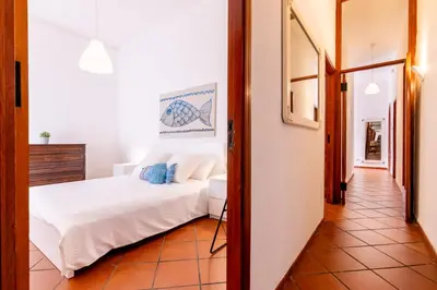 a bedroom with a white bed and a hallway at Vista Mare by DomuSicily in Cinisi