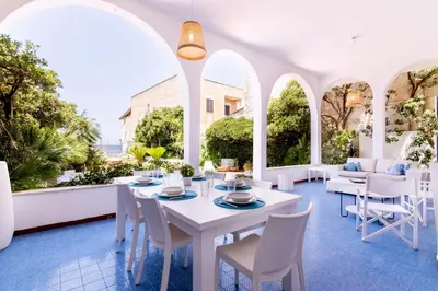 a dining room with white tables and chairs and arched windows at Vista Mare by DomuSicily in Cinisi