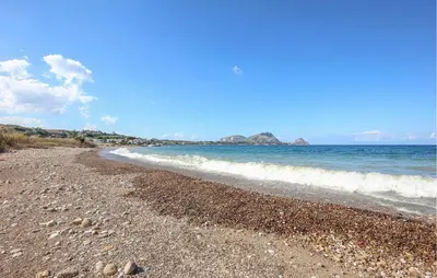 a beach with rocks and the ocean on a sunny day at Awesome Apartment In Trabia in Trabia