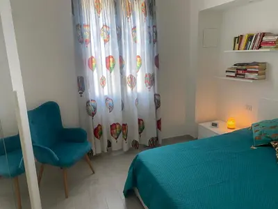 a bedroom with a bed and a blue chair and a curtain at Appartamento Florio in Palermo