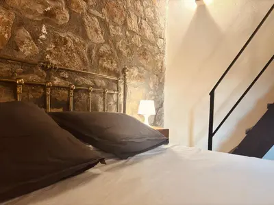 a bedroom with a bed and a stone wall at Le Case di Cardellino - AgriSpa in Sclafani
