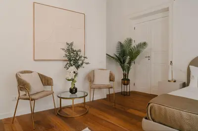 a bedroom with a bed and two chairs and a table at La Duca Suites & Apartments in Palermo
