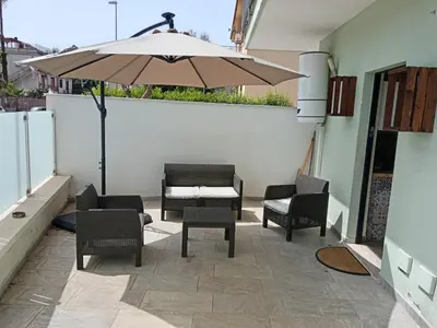 a patio with a table and chairs and an umbrella at Virginia Holiday Home in Mondello
