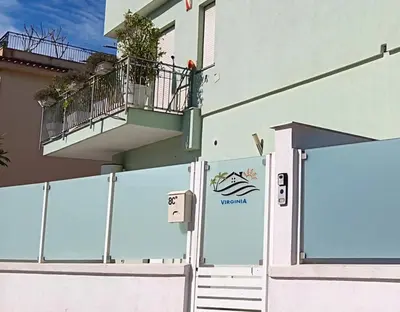 a white building with a balcony and a gate at Virginia Holiday Home in Mondello