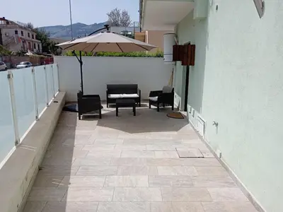 a patio with chairs and an umbrella on a building at Virginia Holiday Home in Mondello