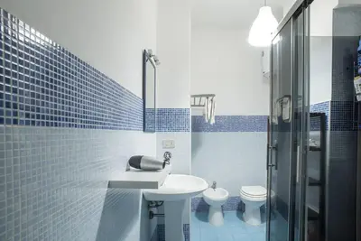 a blue tiled bathroom with a sink and a toilet at New Stabile APT Balcony central apartment in Palermo