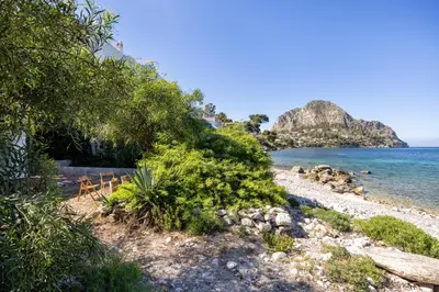 a rocky beach with trees and the ocean at Casa Eugenia in Santa Flavia