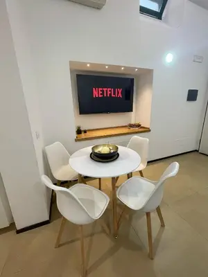 a white table and chairs in a room with a tv at La casa di Alice in Palermo