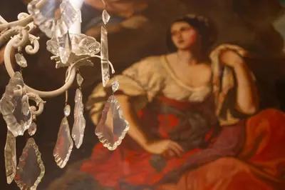 a painting of a woman next to a chandelier at Resuttano Loft in Palermo