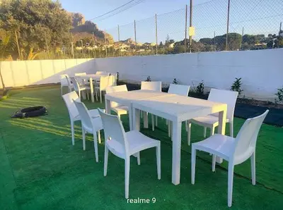 a group of tables and white chairs on the grass at Parco della Vittoria in Terrasini