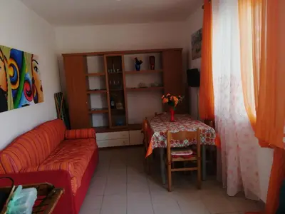 a living room with a table and a red couch at Casa Cinque Torri in San Vito lo Capo