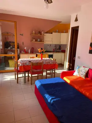 a living room with a table and a kitchen at Casa Cinque Torri in San Vito lo Capo