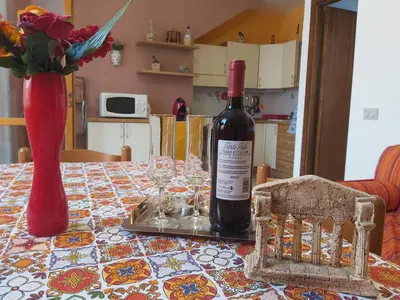a bottle of wine sitting on a table with glasses at Casa Cinque Torri in San Vito lo Capo