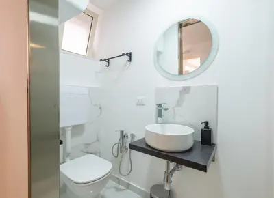 a white bathroom with a sink and a mirror at aprimaManu apartment in Monreale