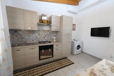 a kitchen with wooden cabinets and a stove top oven at AL Quadrifoglio in Terrasini