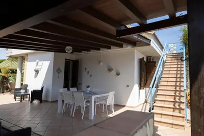 a patio with a table and chairs and stairs at VillaThomas in Campofelice di Roccella
