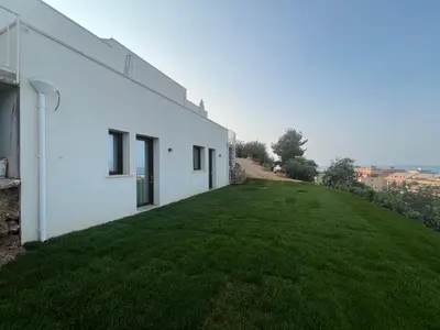 a white house with a green lawn next to it at Tenuta Rapillo in Castellammare del Golfo