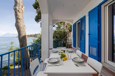 a table on a balcony with a view of the ocean at La Veranda Sul Mare in Santa Flavia