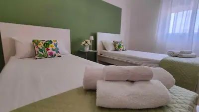 a room with two beds with a ottoman in it at Villa Triscele Holiday Home in Partinico
