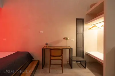 a bedroom with a table and a bed and a chair at Lofterì by DomuSicily in Palermo