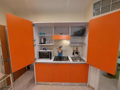 an orange kitchen with a stove and a microwave at Teatro Massimo - Apartment with Private Balcony in Palermo