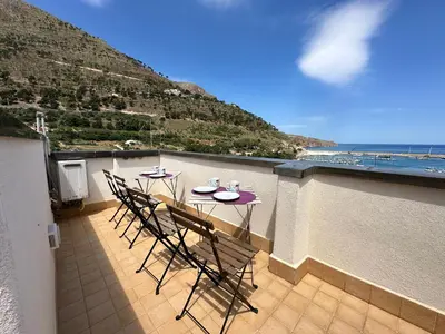 a table and chairs on a balcony with a view of the ocean at Marcantonio Suite in Castellammare del Golfo