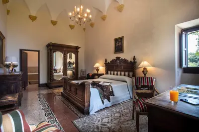 a bedroom with a bed and a table and chairs at Abbazia Santa Maria del Bosco in Contessa Entellina