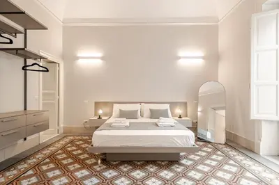 a white bedroom with a bed and a mirror at Zahir Suite Apartment in Palermo