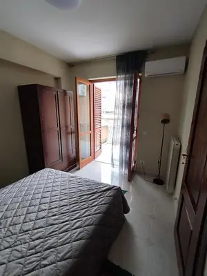a bedroom with a bed and a door to a balcony at V&J appartamenti in Carini