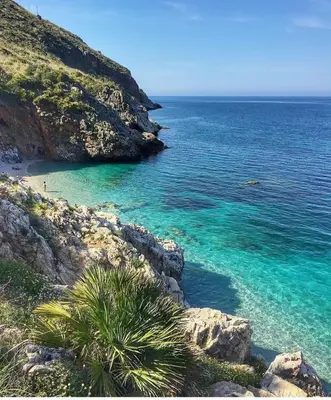 a beach with turquoise water next to a mountain at Casa vinz in Scopello