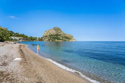 a woman walking on a beach near the water at Casa Trionfante in Santa Flavia