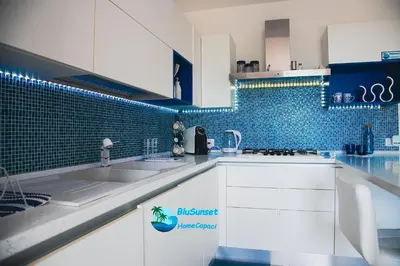 a kitchen with a sink and a blue tiled wall at BluSunset Home Capaci in Capaci