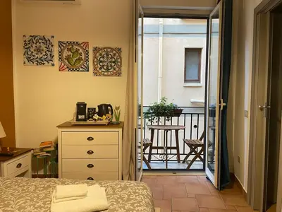 a bedroom with a bed and a balcony with a chair at Punto Politeama in Palermo