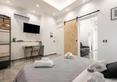 a room with a bed and a desk and a television at Onda blu in Palermo