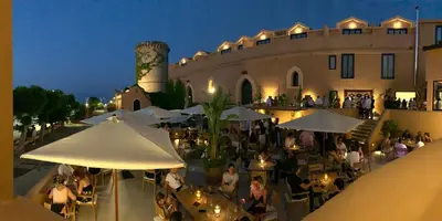 a group of people sitting at tables outside of a building at Daydream in Trabia