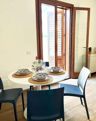a dining room with a white table and chairs at Zahira Apartment in San Vito lo Capo