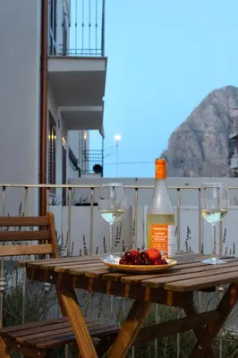 a bottle of wine and two glasses on a wooden table at Zahira Apartment in San Vito lo Capo