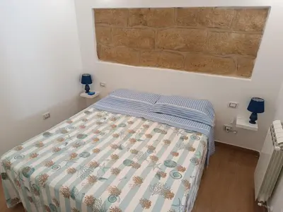 a bedroom with a bed with a comforter on it at Casa Atlanna in Terrasini