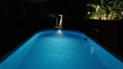 a blue swimming pool at night with a fountain at Villa Aurora Appartamento in villa con piscina in Bagheria