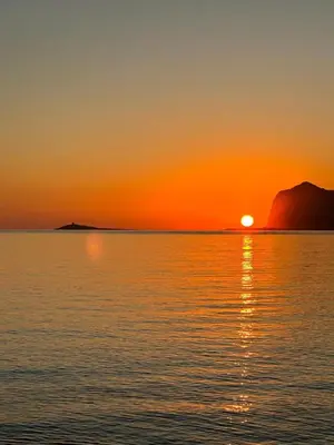 a sunset over the ocean with a mountain in the background at Domus Mea Apartments in Carini